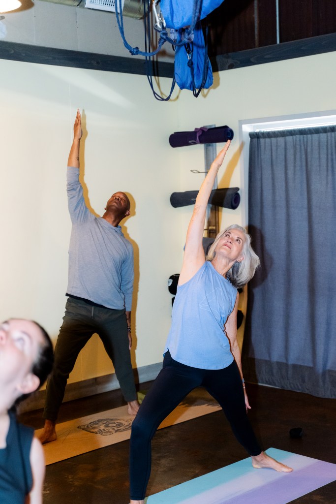 A man and a woman practicing yoga in a yoga studio in reverse warrior